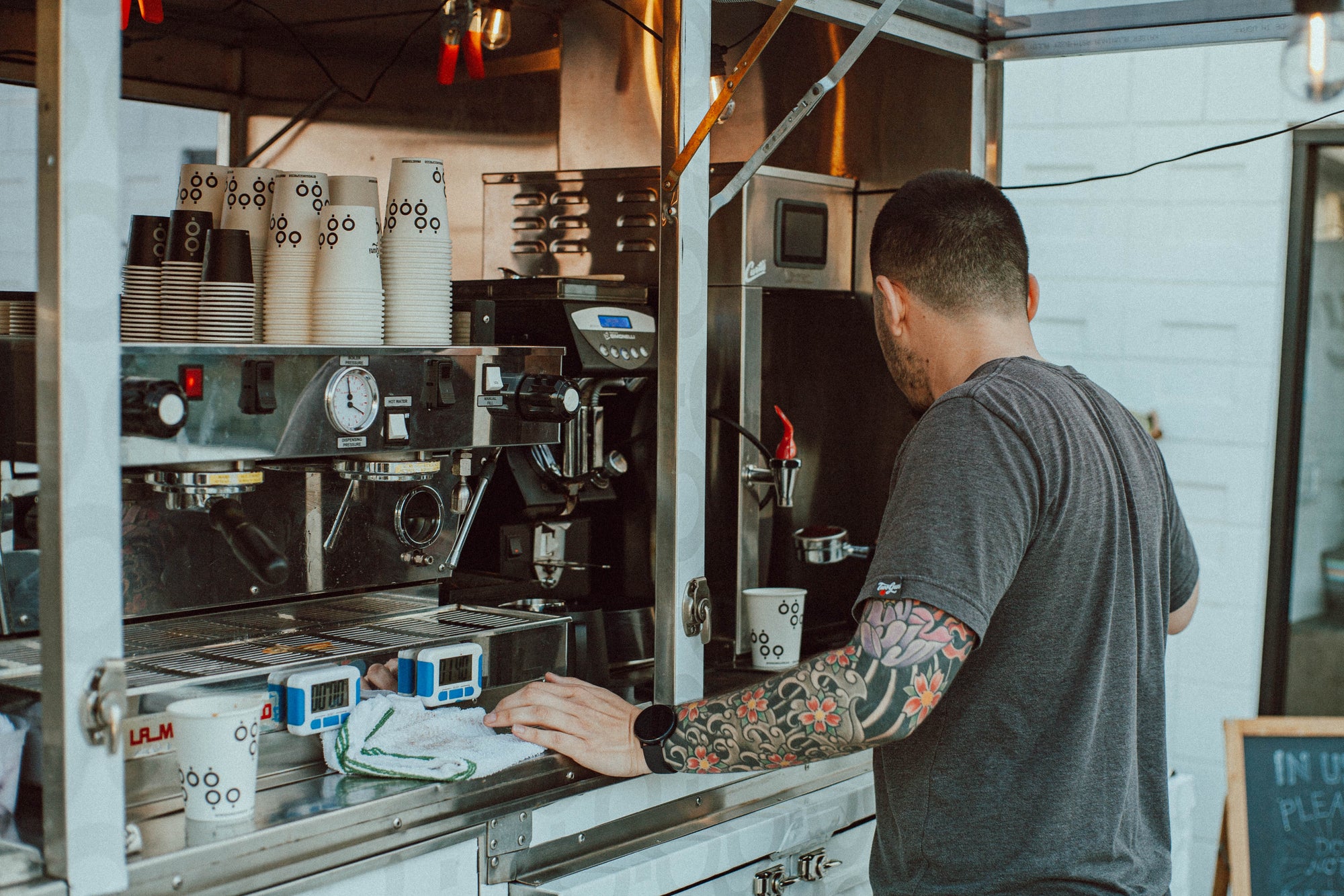 barista standing in front of espresso machine and grinder