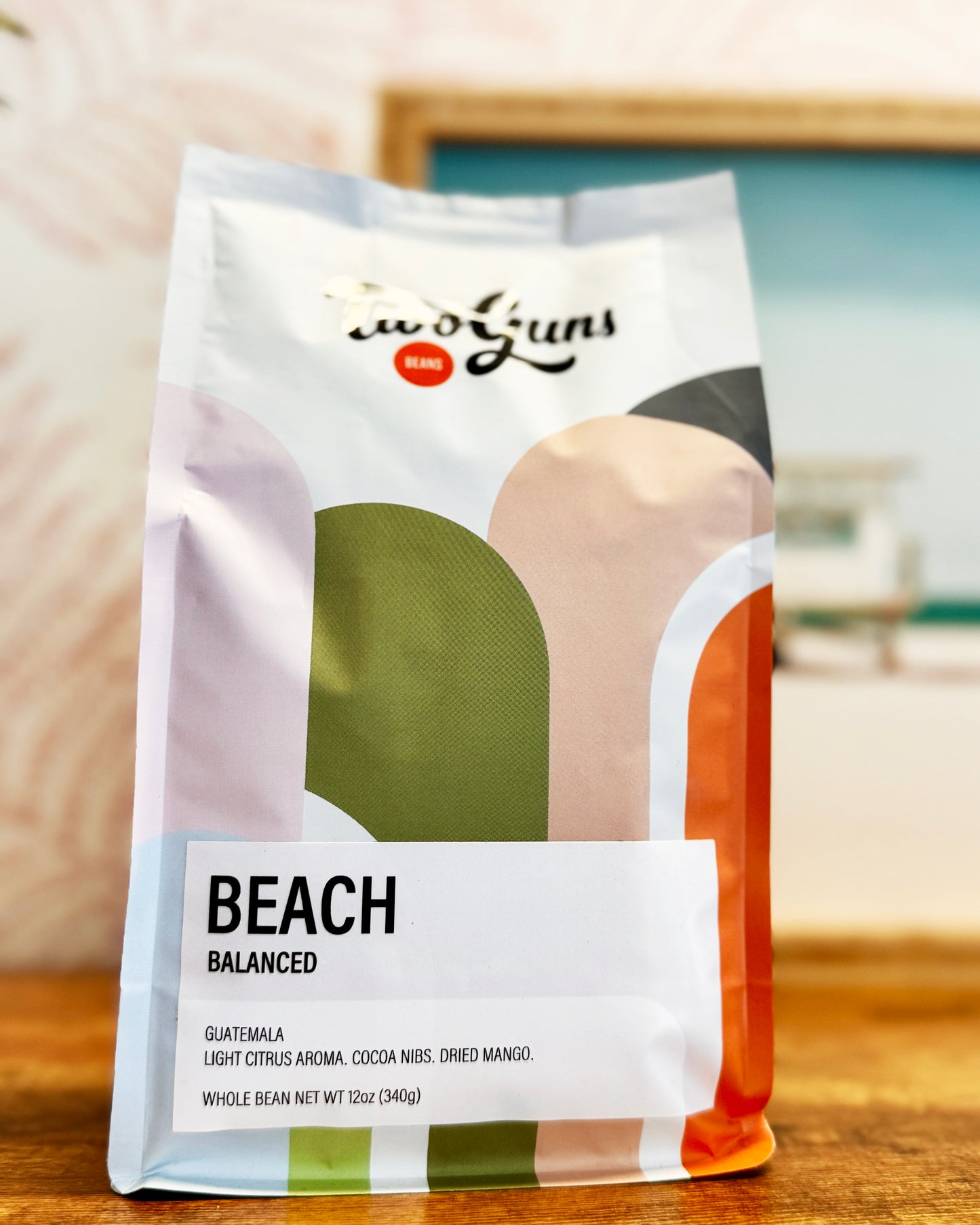 Two Guns Coffee bag labeled 'Beach' on a wooden surface with a blurred background