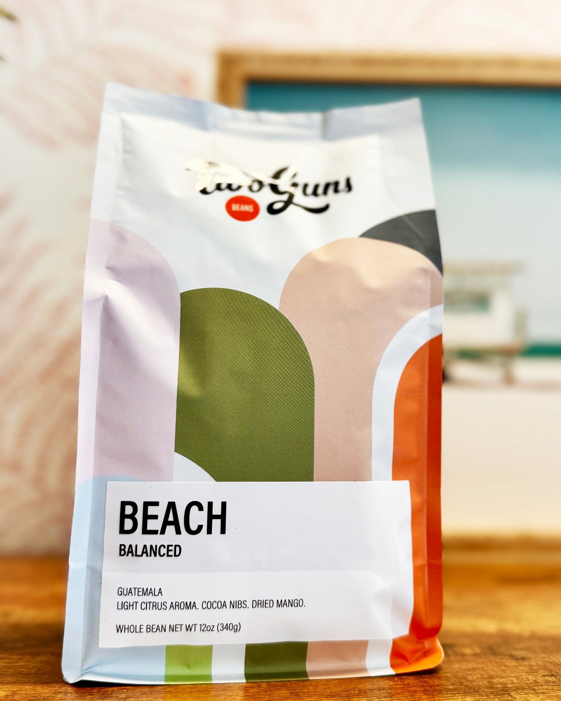 Two Guns Coffee bag labeled 'Beach' on a wooden surface with a blurred background