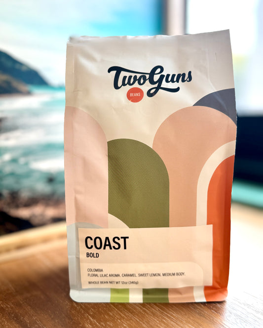 TwoGuns Coast Bold coffee bag on a wooden surface with a blurred natural background