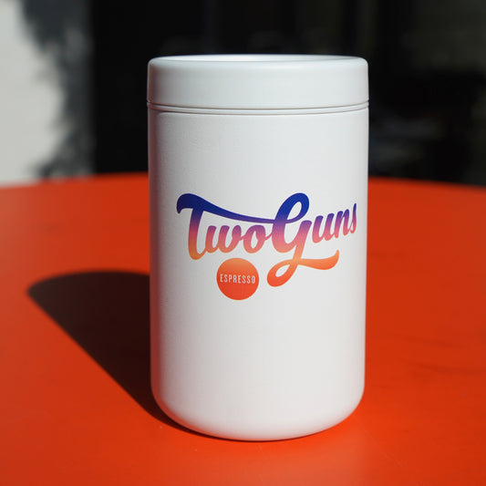 Two Guns ceramic to go tumbler with colorful branding on a blurred background